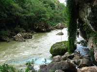 A river of muddy water, with some bright blue water flowing in from one side.