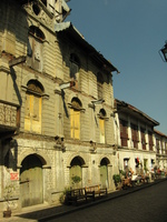 Three storey houses with bits dropping off them and a sign warning about falling debris.