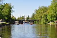 Three men in small inflatable boats floating on the river in front of a bridge.