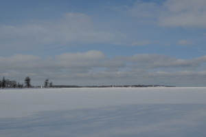 A white surface stretches out into the distance.  On the left a promontory reaches out into the lake.
