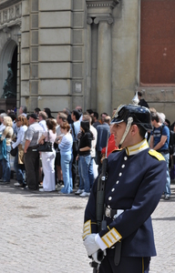 A soldier in ceremonial uniform (complete with spiked helmet) stands guard in front of a crowd of tourists.