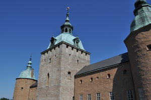 A pale stone castle with three green-roofed towers