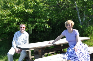 Parents sitting at a picnic table in the sunshine.