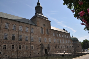 A castle with a moat and tower, in the sunshine.