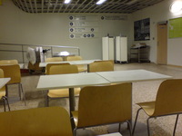 Empty chairs and tables in an airport terminal.  Sign pointing to various parts of the terminal on the wall.