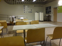 In the cafe at Skavsta airport. Empty chairs and tables in an airport terminal. Sign pointing to various parts of the terminal on the wall.