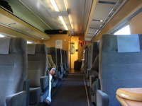 The interior of a first-class railway carriage, decorated in muted colours and wood panelling.