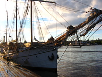 A sailing boat moored to a wooden quay.