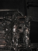 Wooden carvings on the side of a ship, the wood is very dark, almost black.