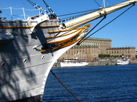 The bowsprit of a white sailing ship frames the Royal Palace.