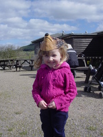 Eve in a magenta cardigan standing on a gravel picnic area.