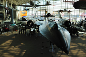 Various aircraft, mostly small, sit on the floor or hang from the ceiling of a large hall.  In the centre is an SR-71 Blackbird